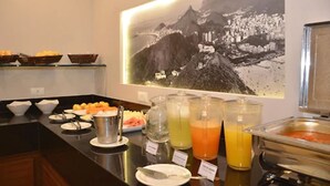 Montaje tipo bufé con diversas opciones de comida y bebidas, una fotografía enmarco de un paisaje montañoso y una zona de cocina moderna.