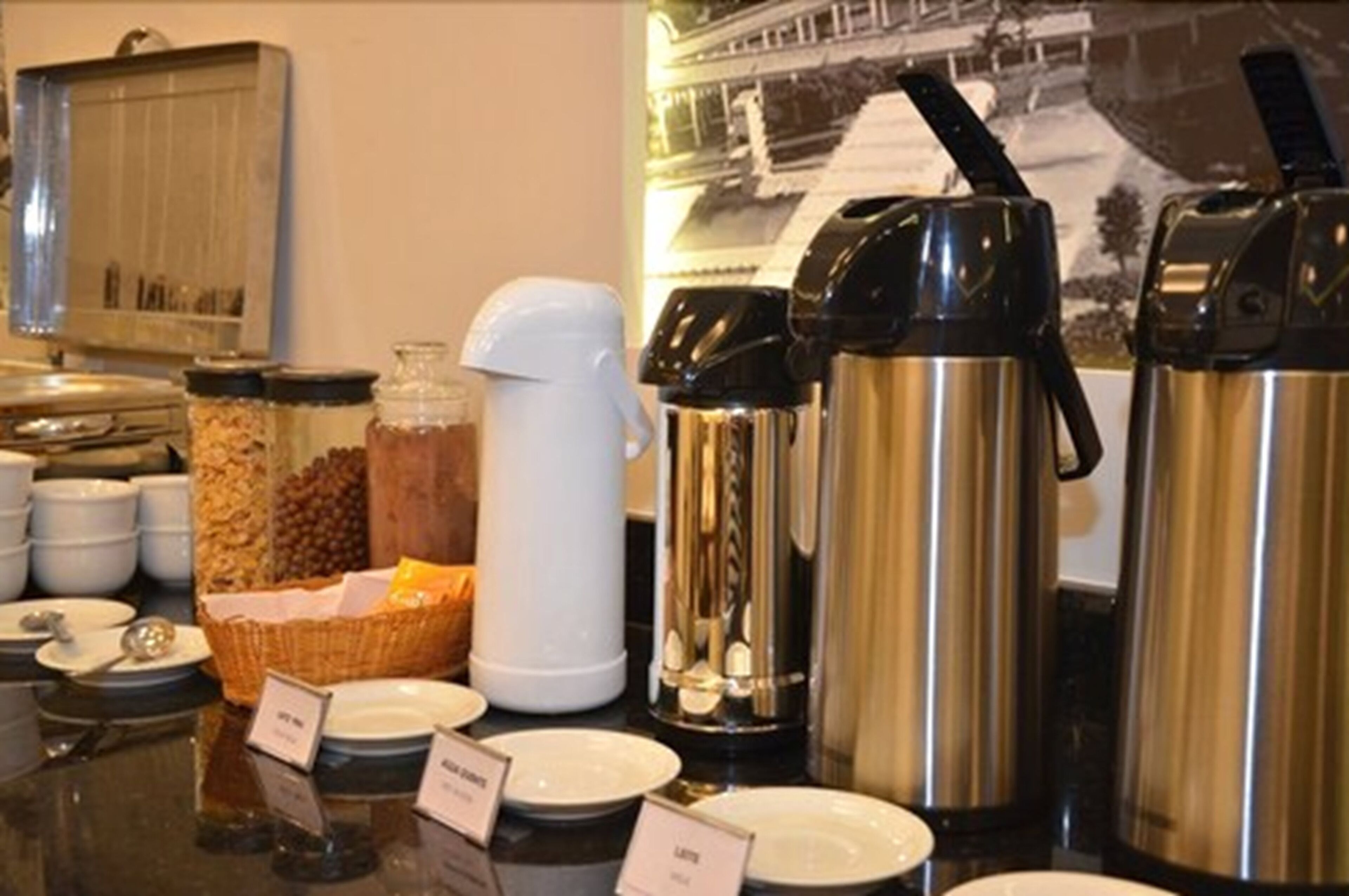 Montaje tipo buffet con diferentes recipientes de comida, una estación de café y un letrero que dice 'Lechuga'.