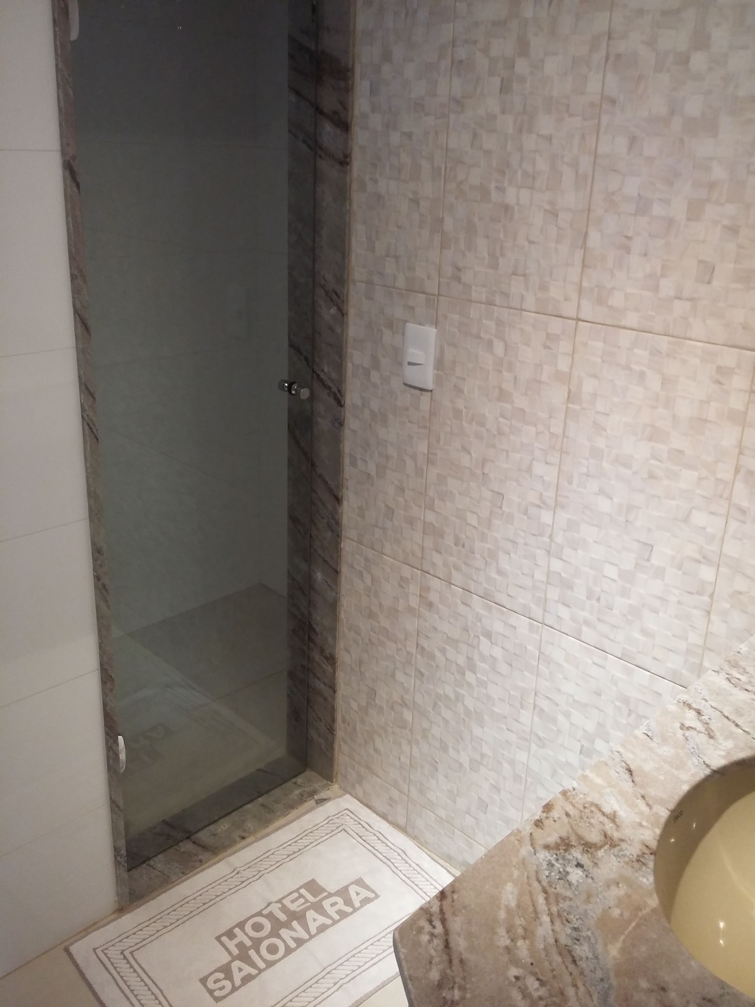 Un bagno con parete rivestita in piastrelle, box doccia in vetro e lavabo in marmo.