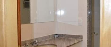 A bathroom with a marble sink, a large mirror, and a shower area.
