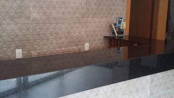Una zona de recepción con mostrador negro, azulejos con diseño y un armario de madera.
