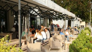 Un espace extérieur aménagé avec des tables et des chaises, une allée couverte et une enseigne indiquant l’emplacement d’un restaurant.