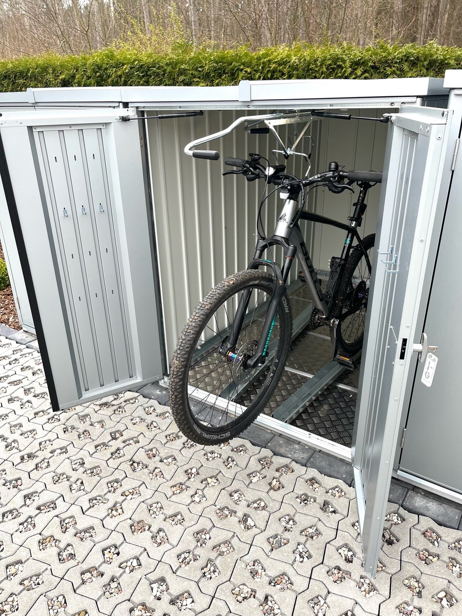A grey metal shed with a bicycle inside.