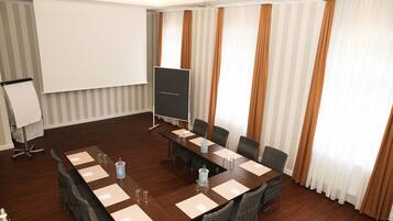 A conference room with a long table, chairs, a projector screen, and a whiteboard.