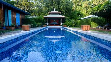 Una piscina al aire libre, sillones reclinables de piscina