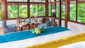 A room with a bed, a table, chairs, and a view of palm trees. - Blue Osa Beach Resort and Spa (Puerto Jiménez)