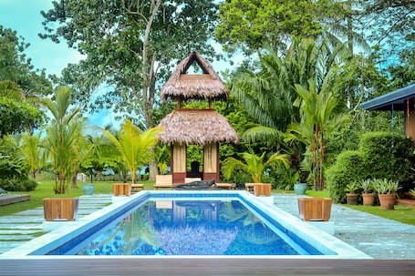 Una piscina al aire libre, sillones reclinables de piscina