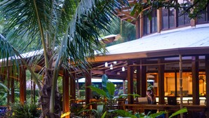 An indoor garden with a wooden structure, lush greenery, and a person working at a desk. - Blue Osa Beach Resort and Spa (Puerto Jiménez)