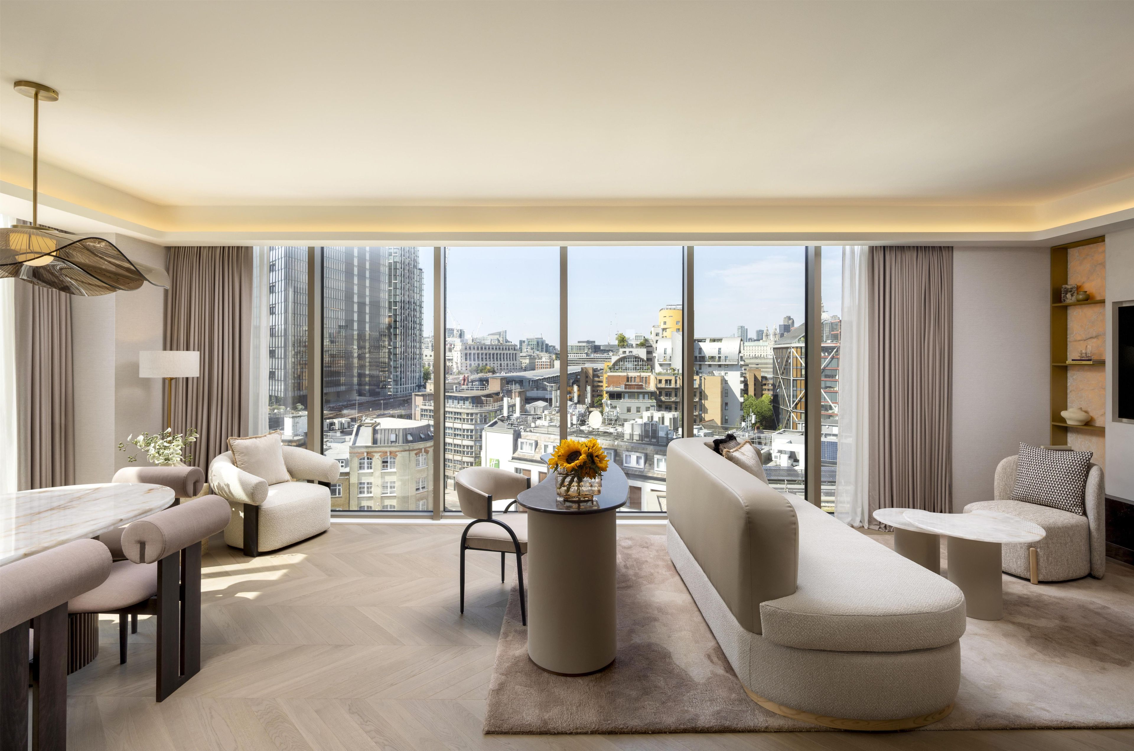 Un salon moderne avec une grande vue sur la ville, une table basse ronde et un canapé.