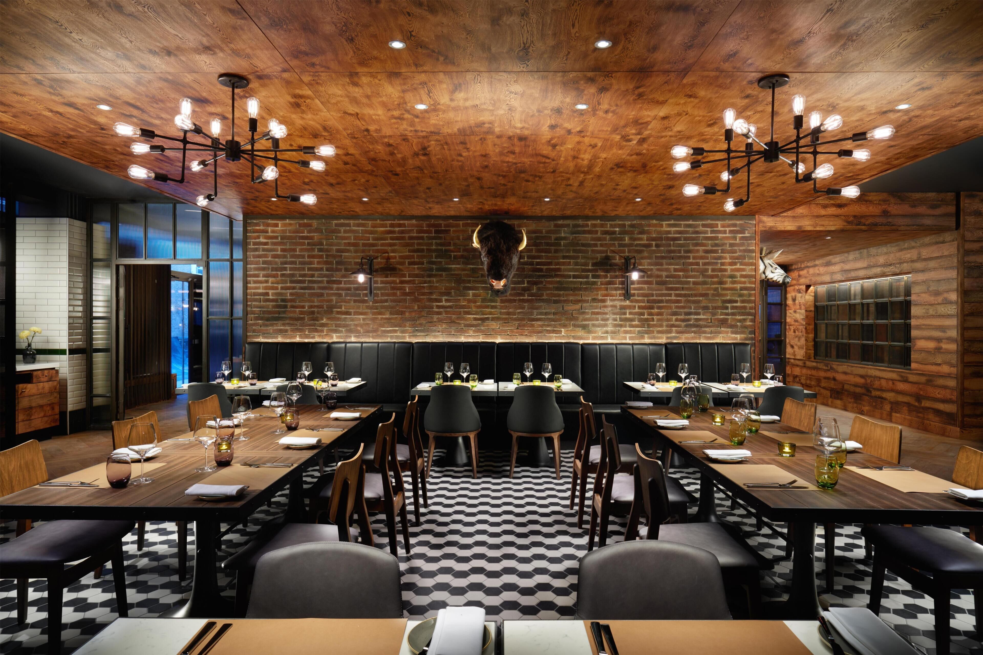 Un restaurante con una larga mesa común, cabinas y un techo de madera.