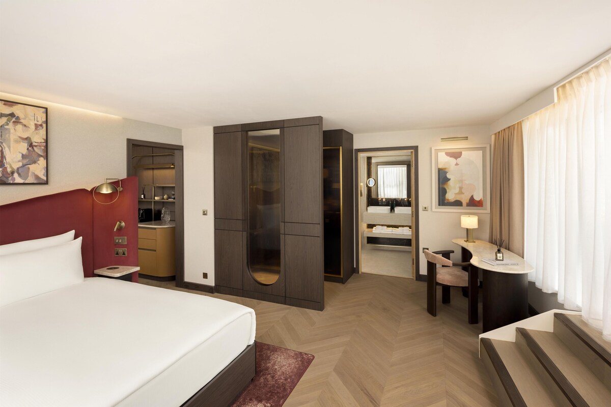 Una habitación de hotel con cama, escritorio, espejo y armario.