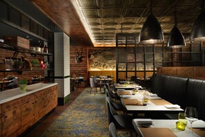 A restaurant interior with wooden cabinetry, a patterned carpet, and a long dining table with multiple chairs. - Hilton London Bankside (London)