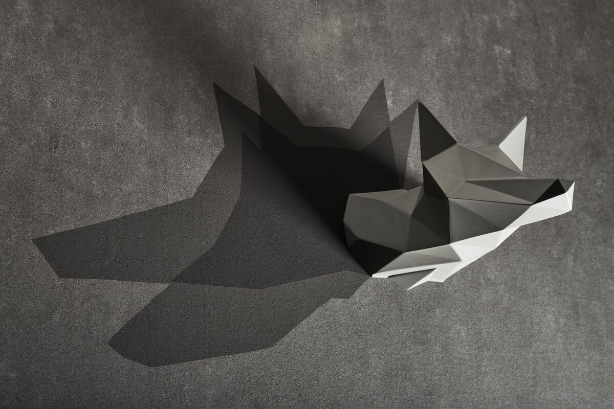 Una escultura abstracta y geométrica sobre una superficie gris con textura.
