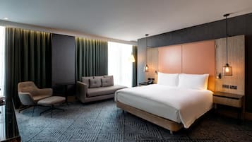 Ein modernes Hotelzimmer mit einem großen Bett, einer Couch, einem Sessel und einem Schreibtisch.