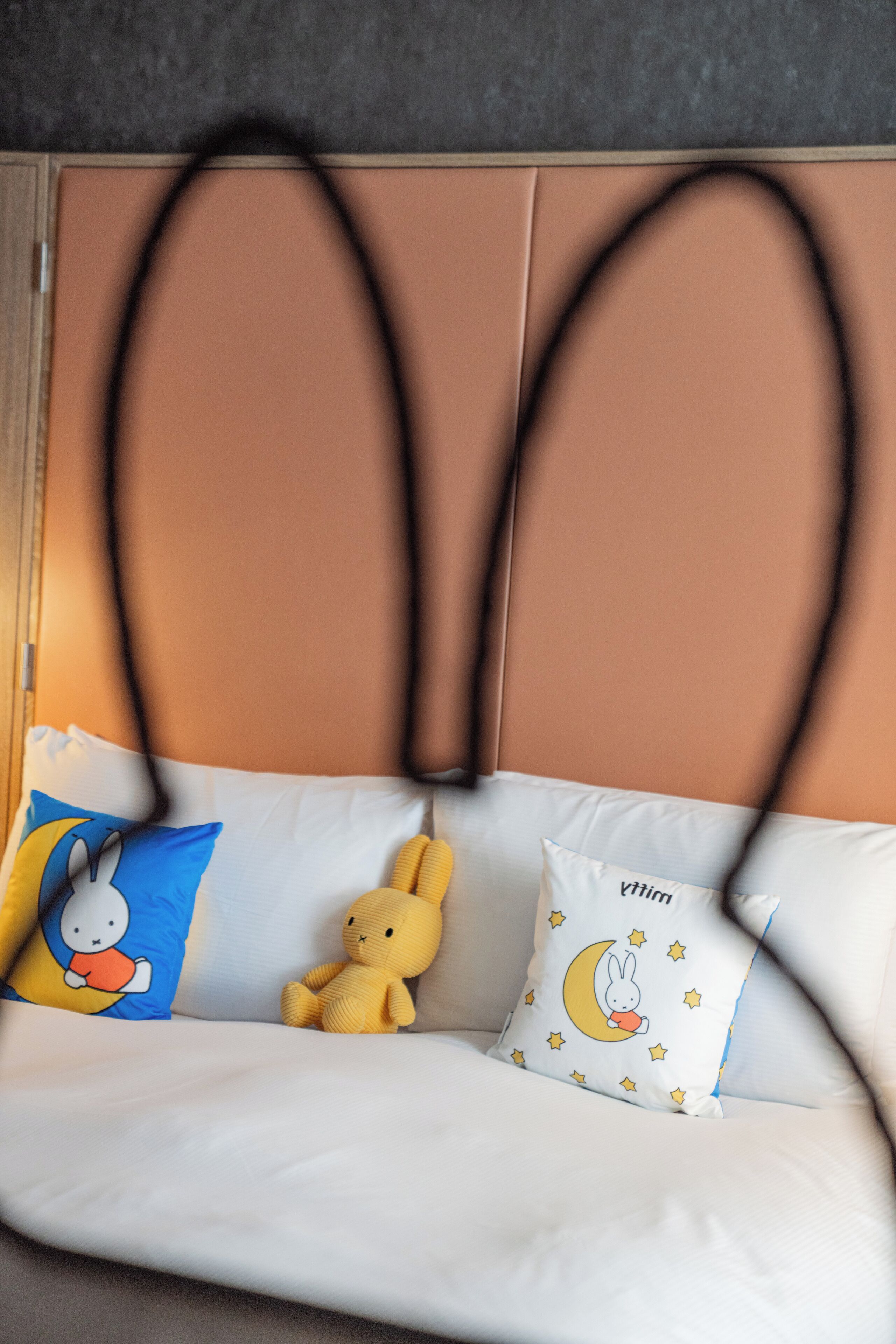 Un canapé blanc avec deux coussins : l’un représente un lapin de dessin animé et l’autre, une lune entourée d’étoiles.