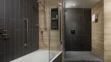 A modern bathroom with a glass-enclosed shower, a white bathtub, and a small shelf with toiletries.