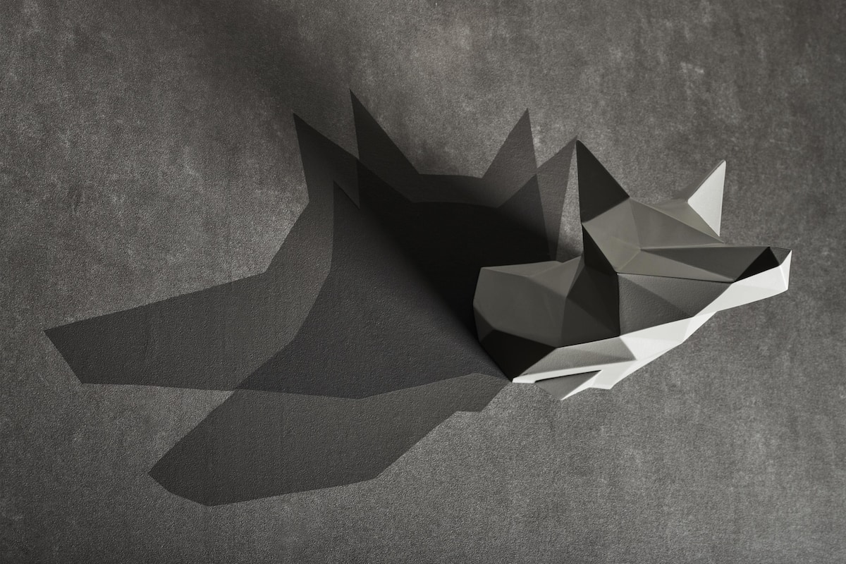 Una escultura abstracta y geométrica sobre una superficie gris con textura.