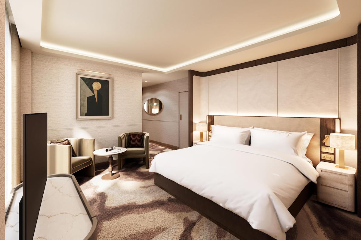 Una habitación de hotel moderna con una cama grande, un escritorio, una silla, un espejo redondo y un televisor.