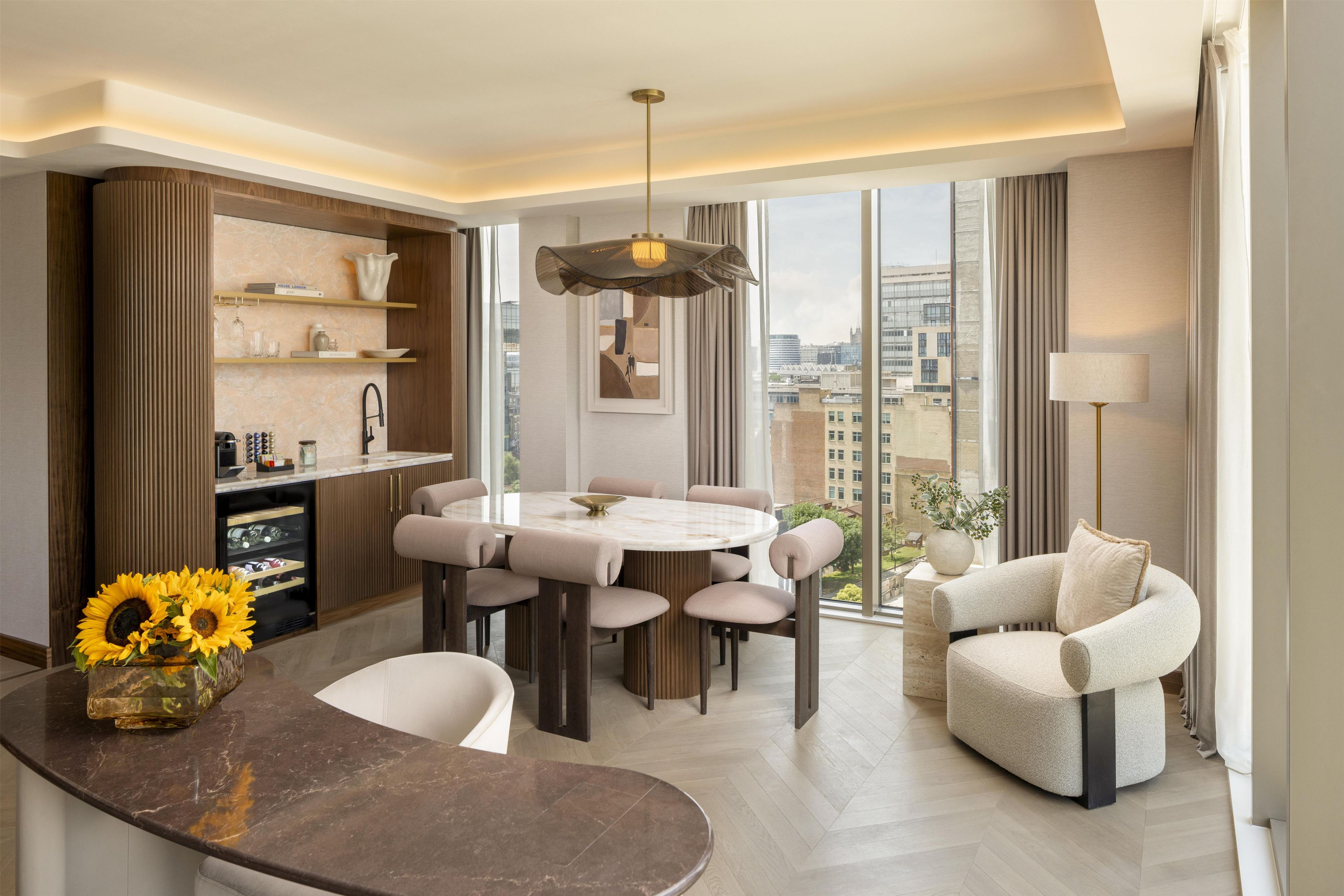 A modern living room with a dining area, a sofa, and a view of the city.