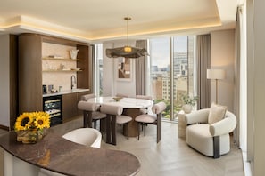 A modern living room with a dining area, a sofa, and a view of the city. - Hilton London Bankside (London)
