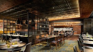 A restaurant with multiple dining tables, chairs, and hanging pendant lights. - Hilton London Bankside (London)