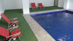 A swimming pool with red lounge chairs and artificial grass. - Premier Inn Tuxtla (Tuxtla Gutierrez)
