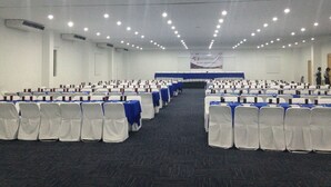 A conference room with rows of white chairs, blue tablecloths, and a stage at the front. - Premier Inn Tuxtla (Tuxtla Gutierrez)