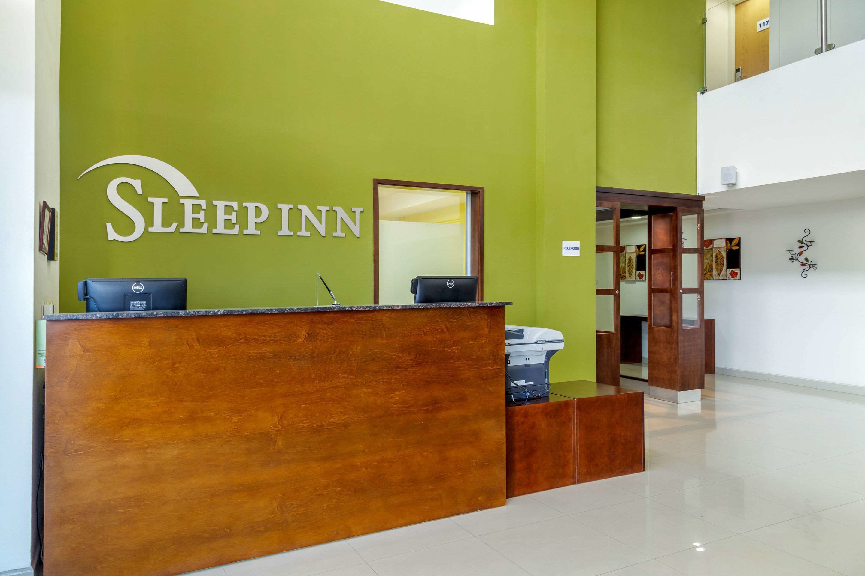 Una recepción con una pared verde y un letrero que dice "Sleepinn".