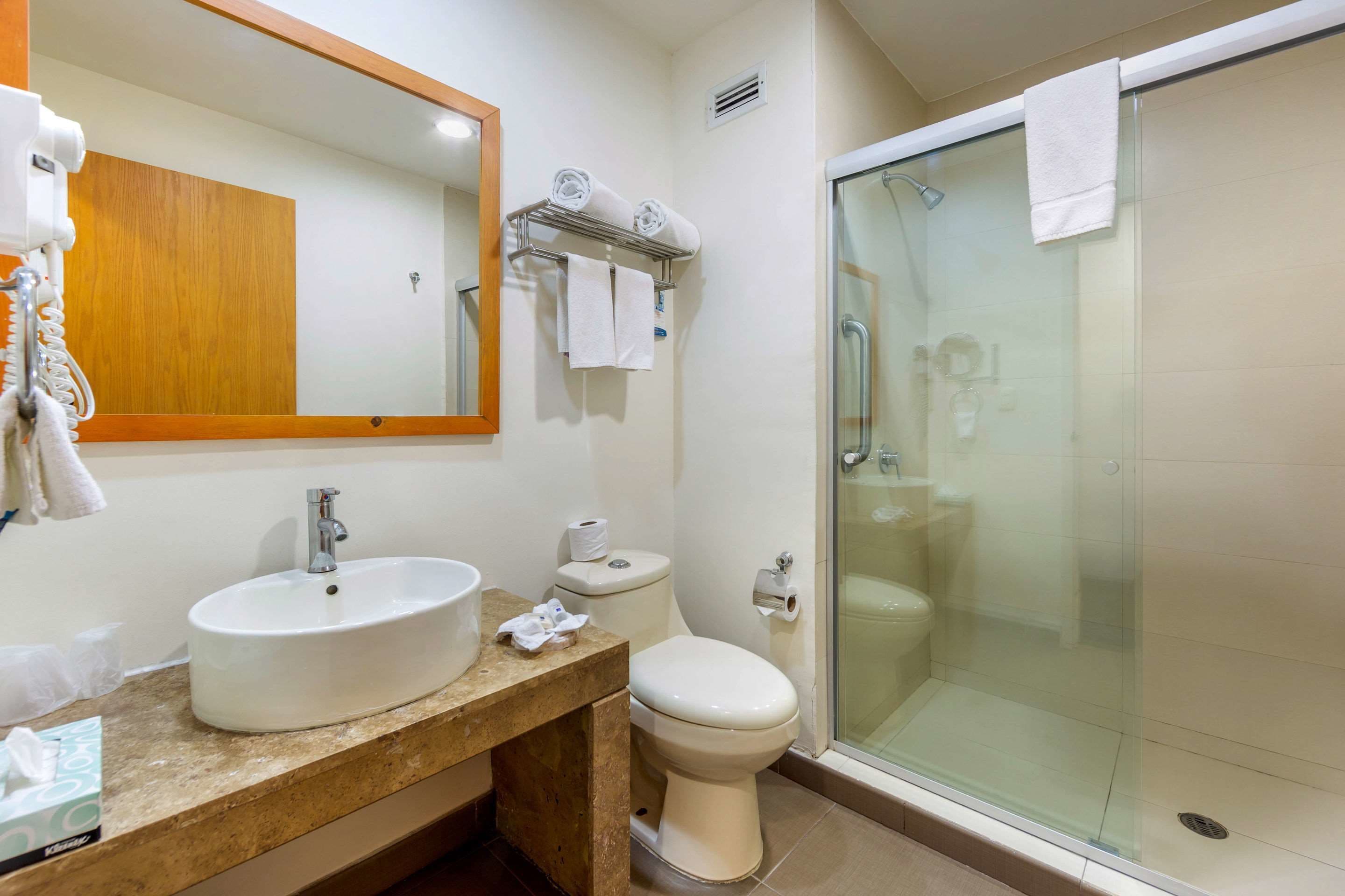 Un baño con lavamanos, inodoro y cabina de ducha de vidrio.