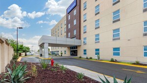 A modern hotel with a flat roof, multiple windows, and a covered entrance.