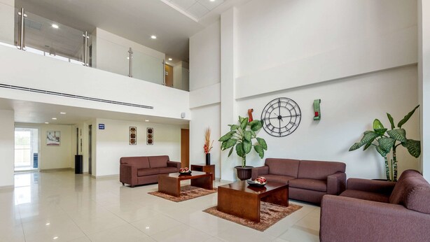 A spacious lobby with a high ceiling, two sofas, a coffee table, and potted plants.