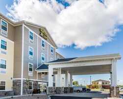 A MainStay Suites hotel with a covered parking area and a clear sky.
