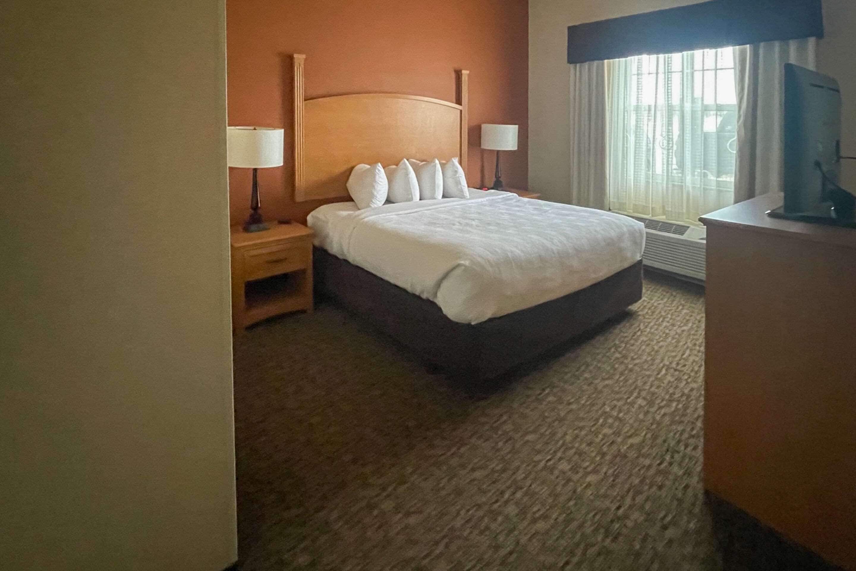 Una habitación de hotel con cama, mesitas de noche, un escritorio y televisor.