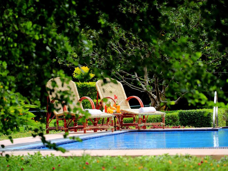 A poolside area with wicker lounge chairs and a pool.