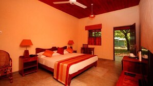 A bedroom with a bed, two nightstands, a desk, a chair, a ceiling fan, and a window with curtains. - Governor's Gangula (Dambulla)