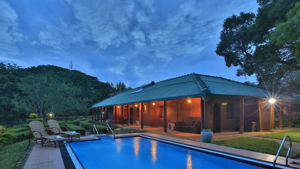 A swimming pool with lounge chairs and a covered patio area. - Governor's Gangula (Dambulla)