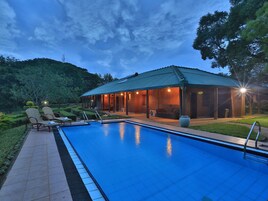 Una piscina con sillones de descanso y un área de terraza techada.