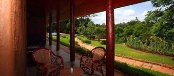 Un espacio al aire libre cubierto con mobiliario de mimbre y vistas a un jardín ajardinado.