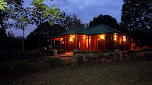 A wooden cabin with a green roof, surrounded by a garden with various plants and flowers. - Governor's Gangula (Dambulla)
