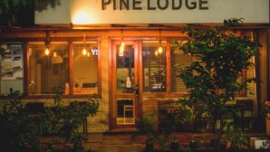 The exterior of Pine Lodge, featuring a wooden facade, large windows with blinds, and a welcoming entrance. - Pine Lodge Maldives (Hulhumalé)