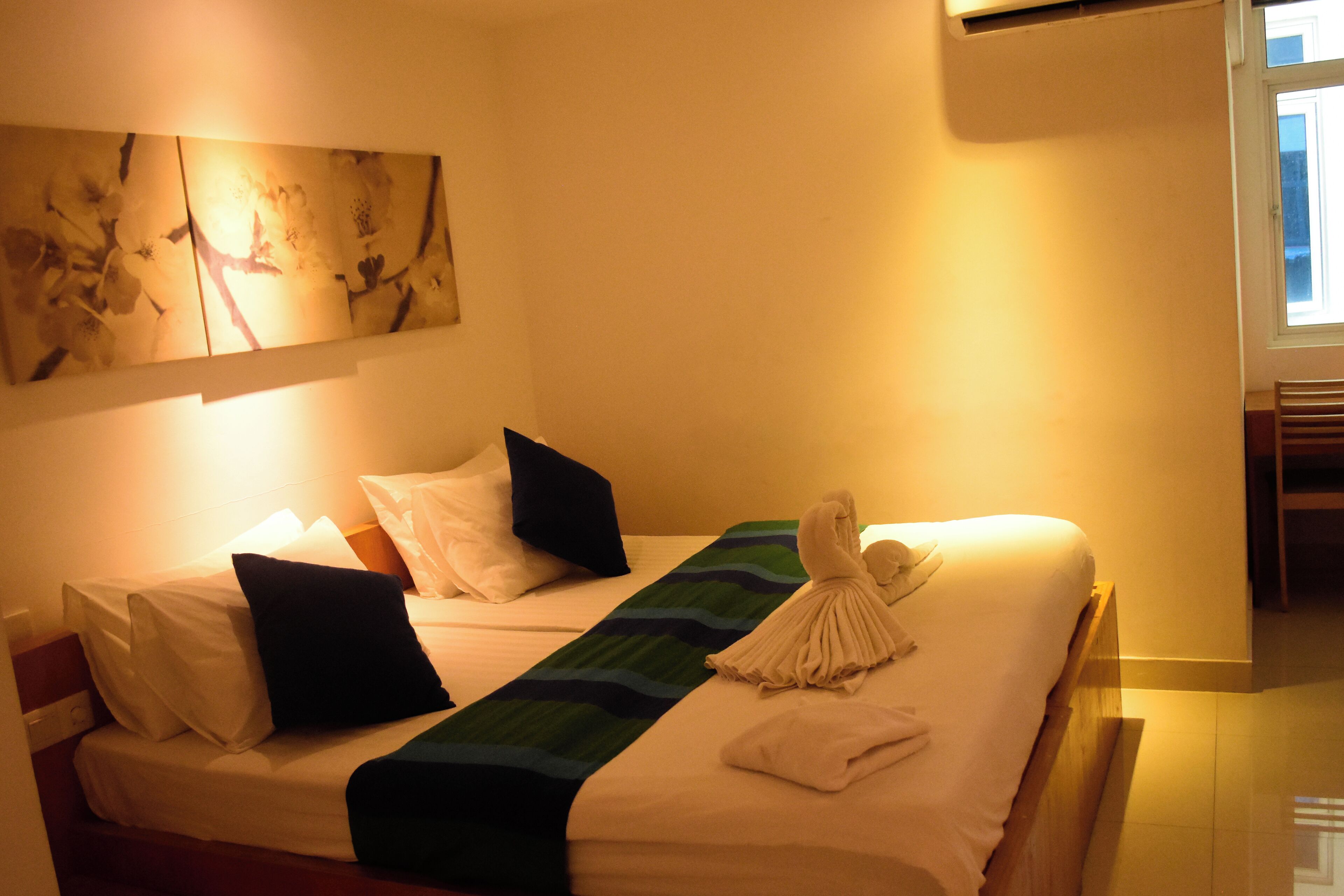 Una habitación de hotel con cama, almohadas, una toalla y un cuadro en la pared.