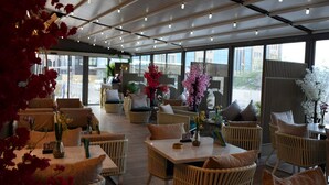 A modern indoor seating area with wicker furniture and large windows. - Saraya Corniche Hotel (Doha)