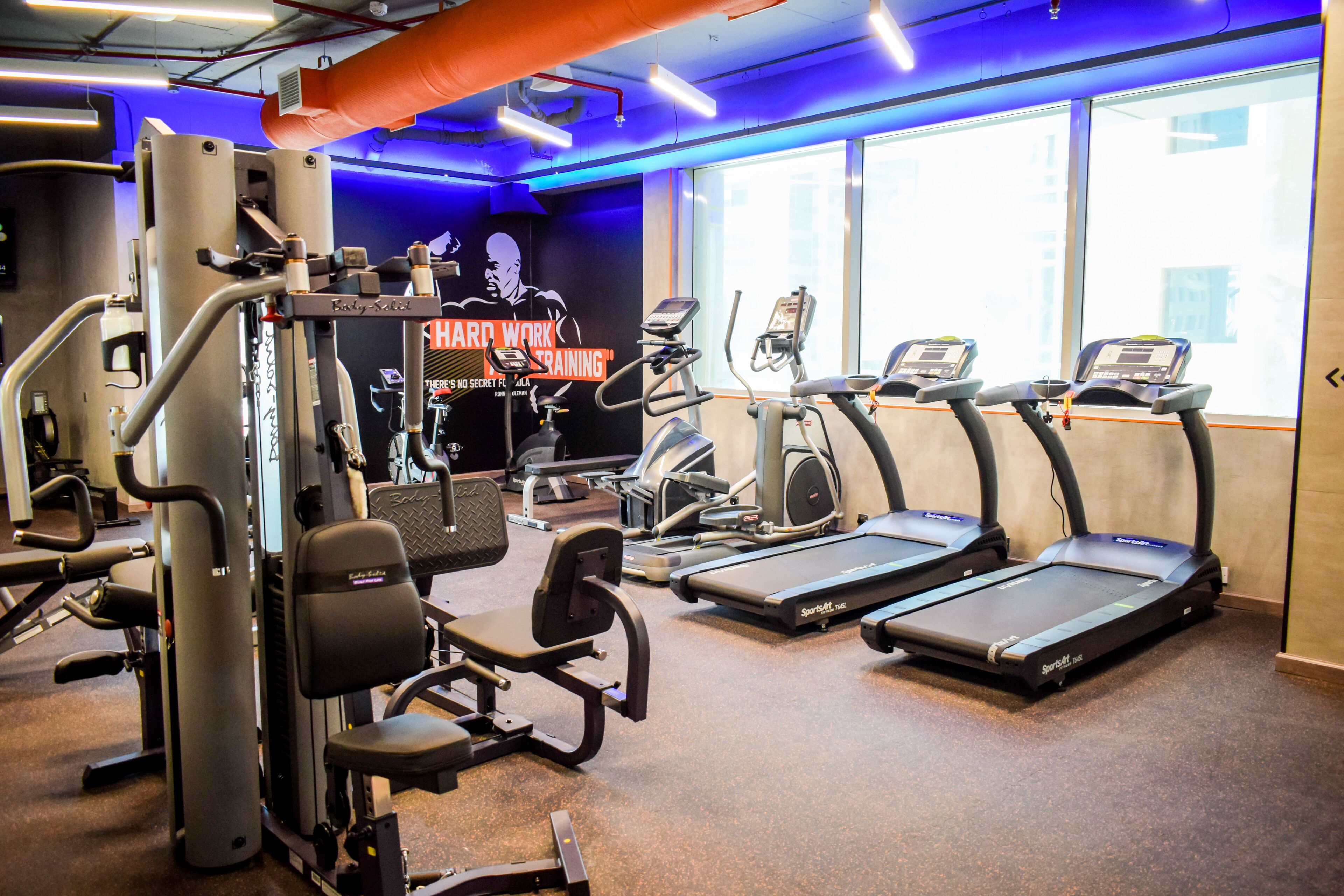 A gym with treadmills, weight machines, and a large mirror.