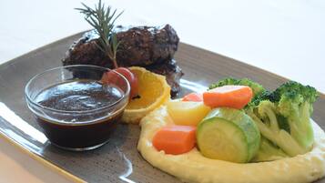 Um prato com bife, legumes e molho.