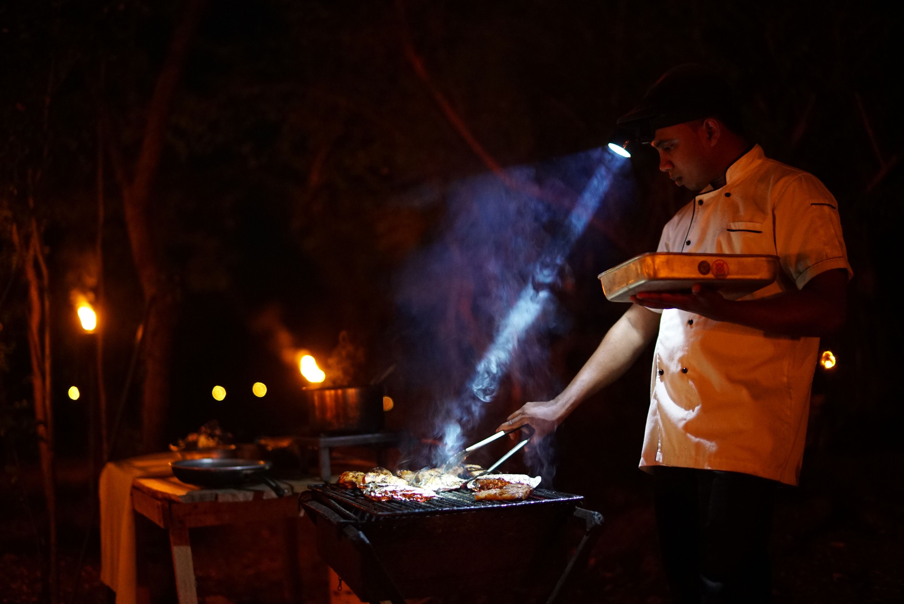 A person grilling food outdoors at night.