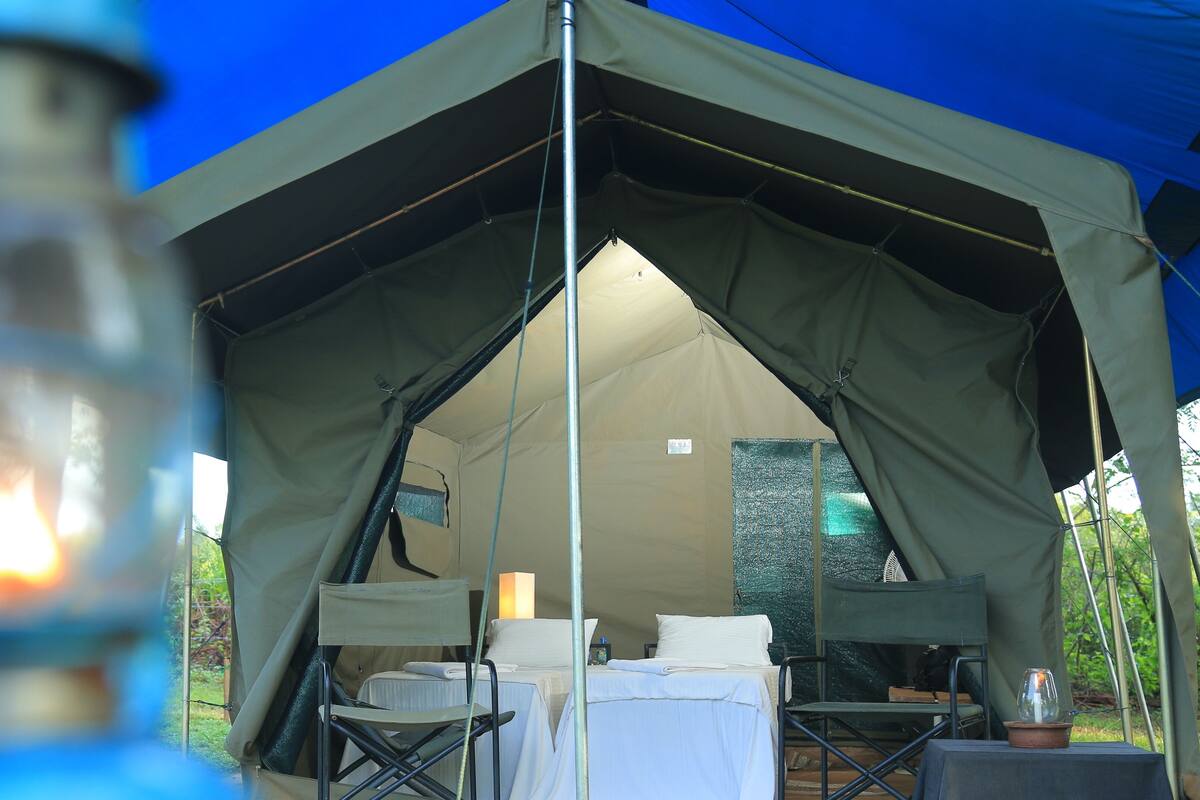 A tent with a bed, a table, and a chair inside.