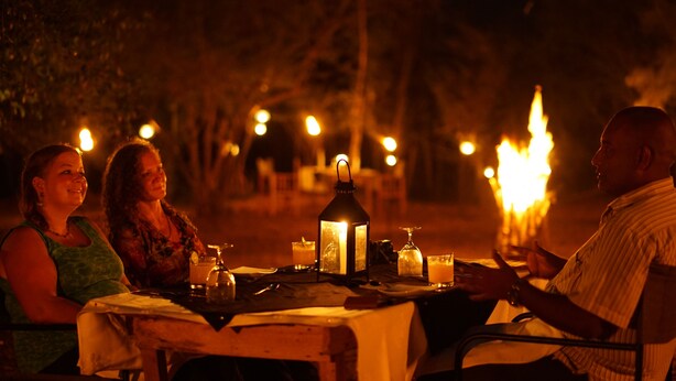 A table set outdoors at night with candles and a lantern, surrounded by trees. - Big Game - Udawalawe by Eco Team (Thanamalvila)