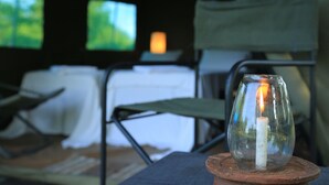 A candle in a glass holder on a wooden coaster, a chair, and a table with a white tablecloth. - Big Game - Wilpattu by Eco Team (Pahala Maragahawewa)