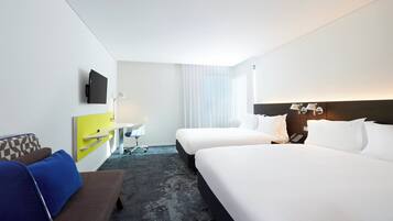 A hotel room with two beds, a desk, a chair, a TV, and a phone.