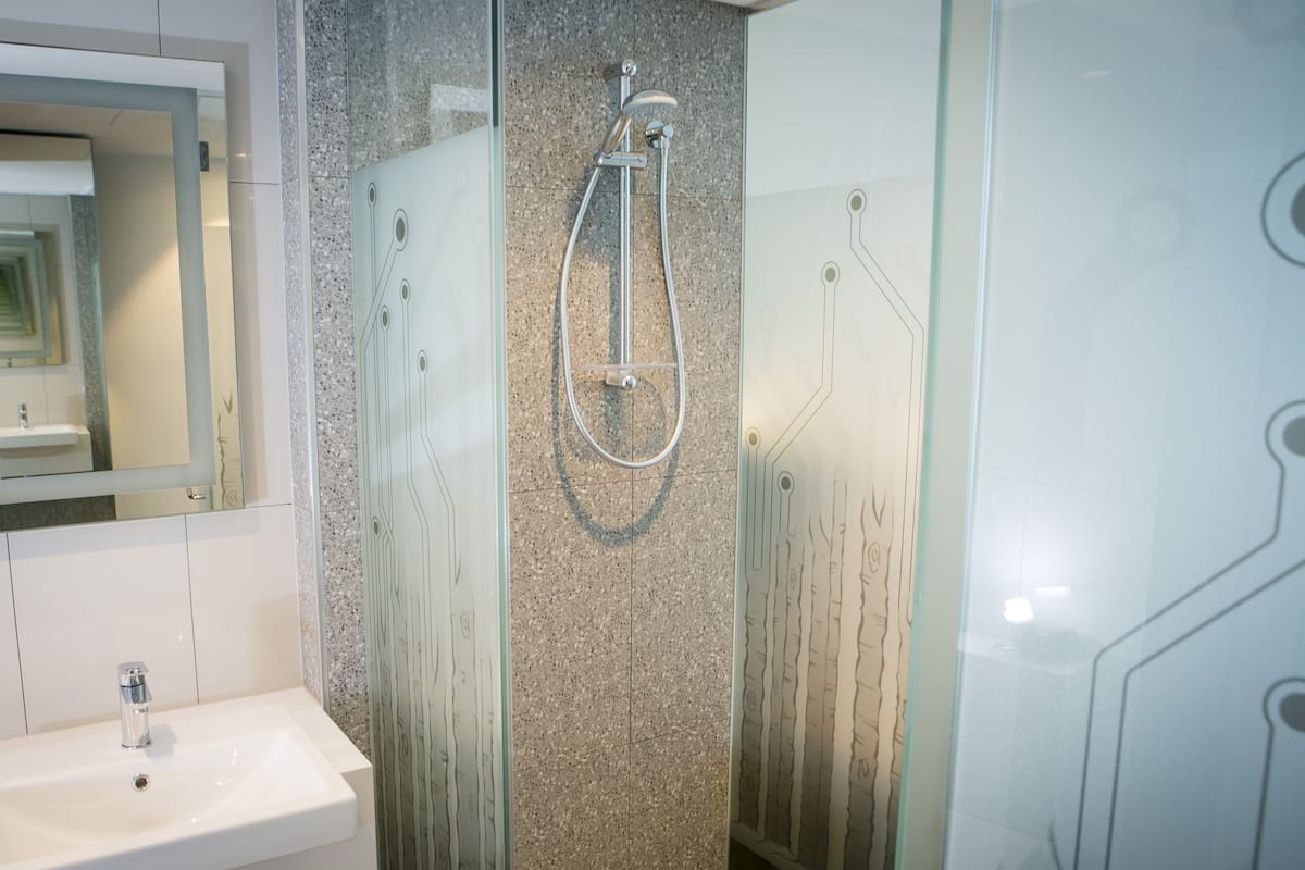 Un baño moderno con cabina de ducha de vidrio, lavamanos blanco y espejo.